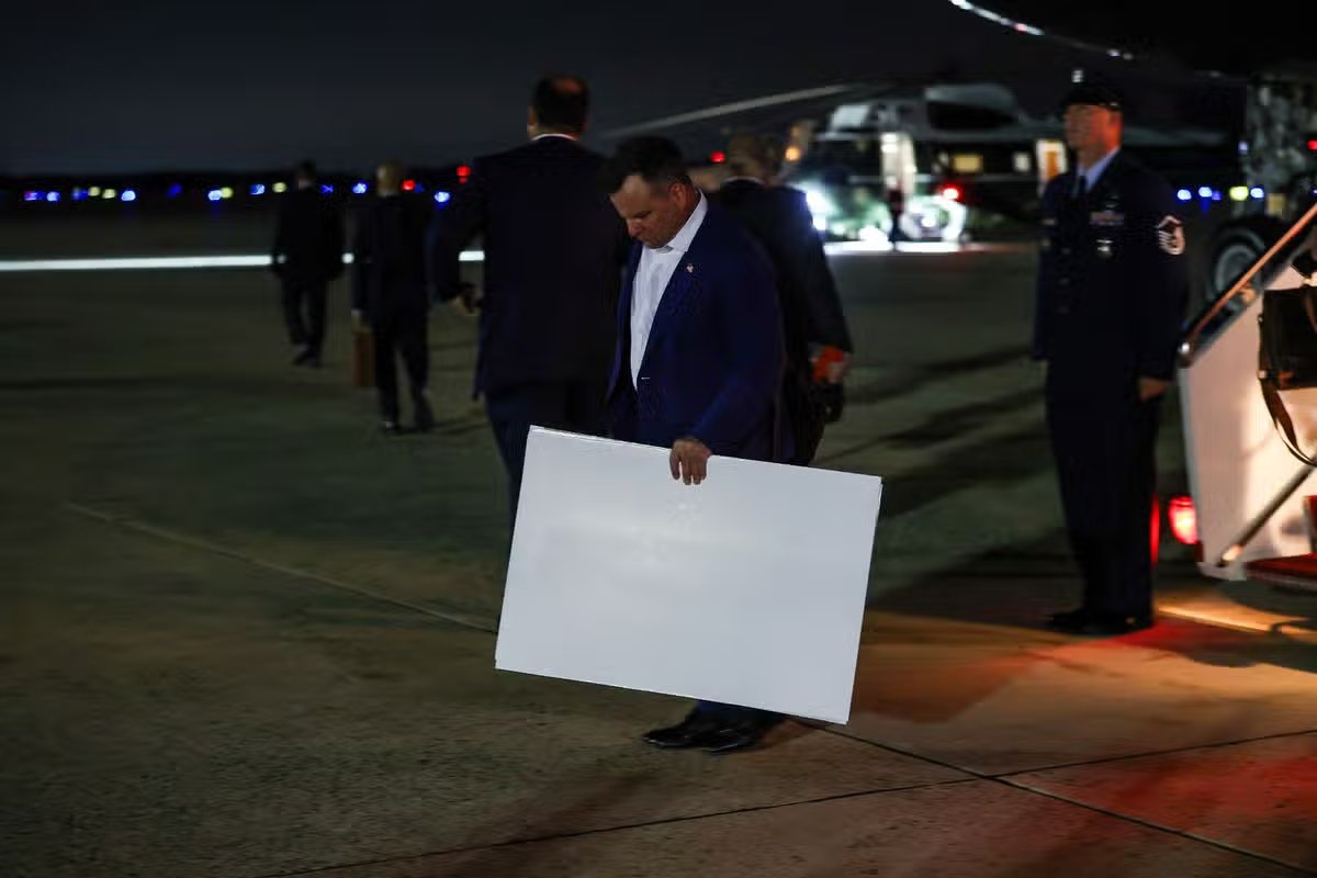 El director de la Agencia Federal de Financiamiento de la Vivienda, Bill Pulte, sigue al presidente Donald Trump desde el Air Force One sosteniendo una cartulina
