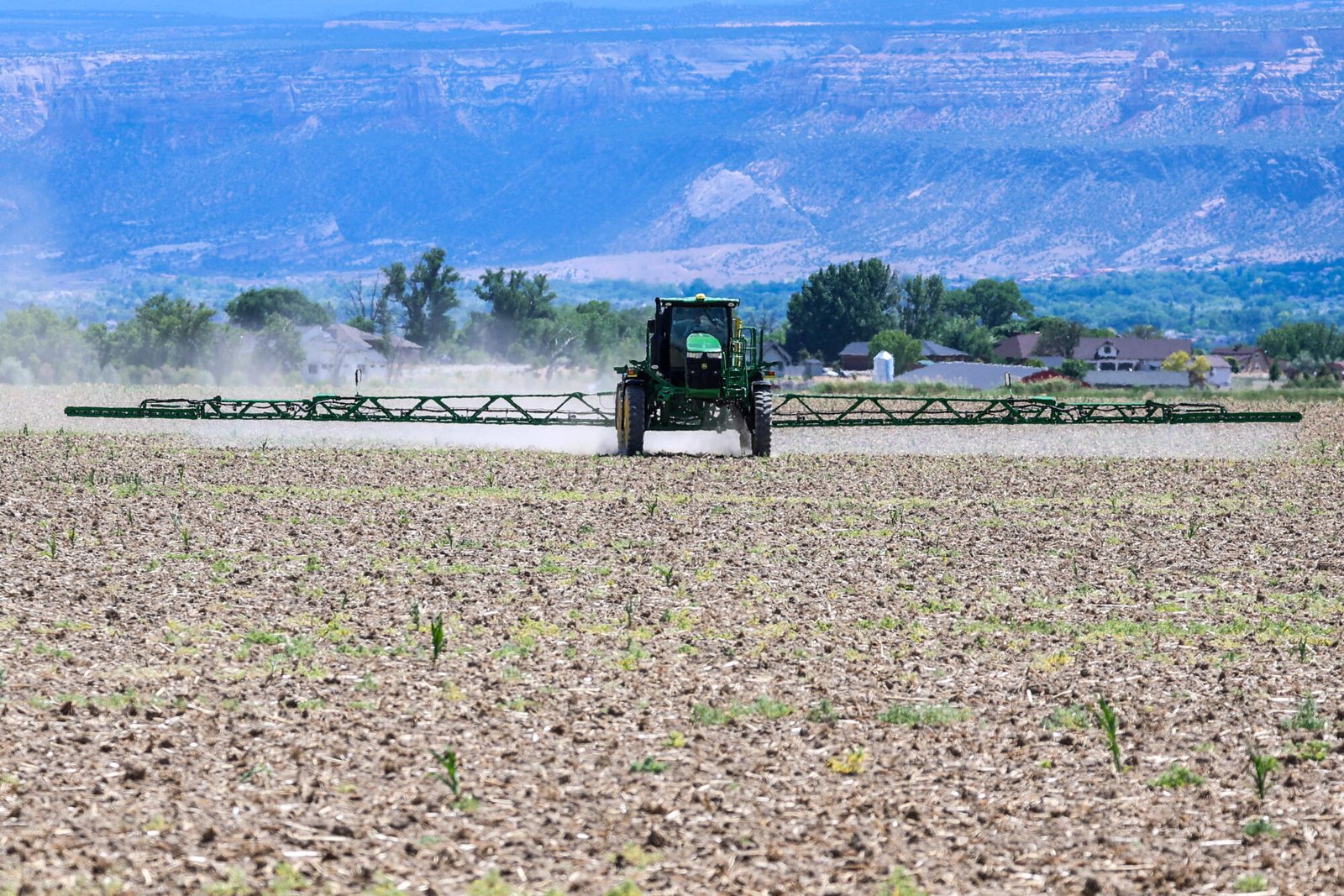 Un tractor rocía herbicida en un campo.
