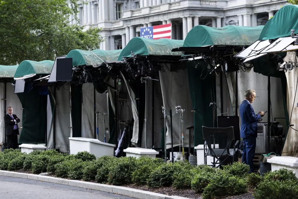 Los corresponsales de televisión de la Casa Blanca se preparan para transmitir en vivo junto al lugar de transmisión vacante de CNN en los terrenos de la Casa Blanca.