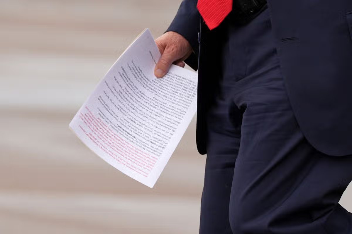 El presidente Donald Trump sostiene un documento cuando llega a bordo del Air Force One.