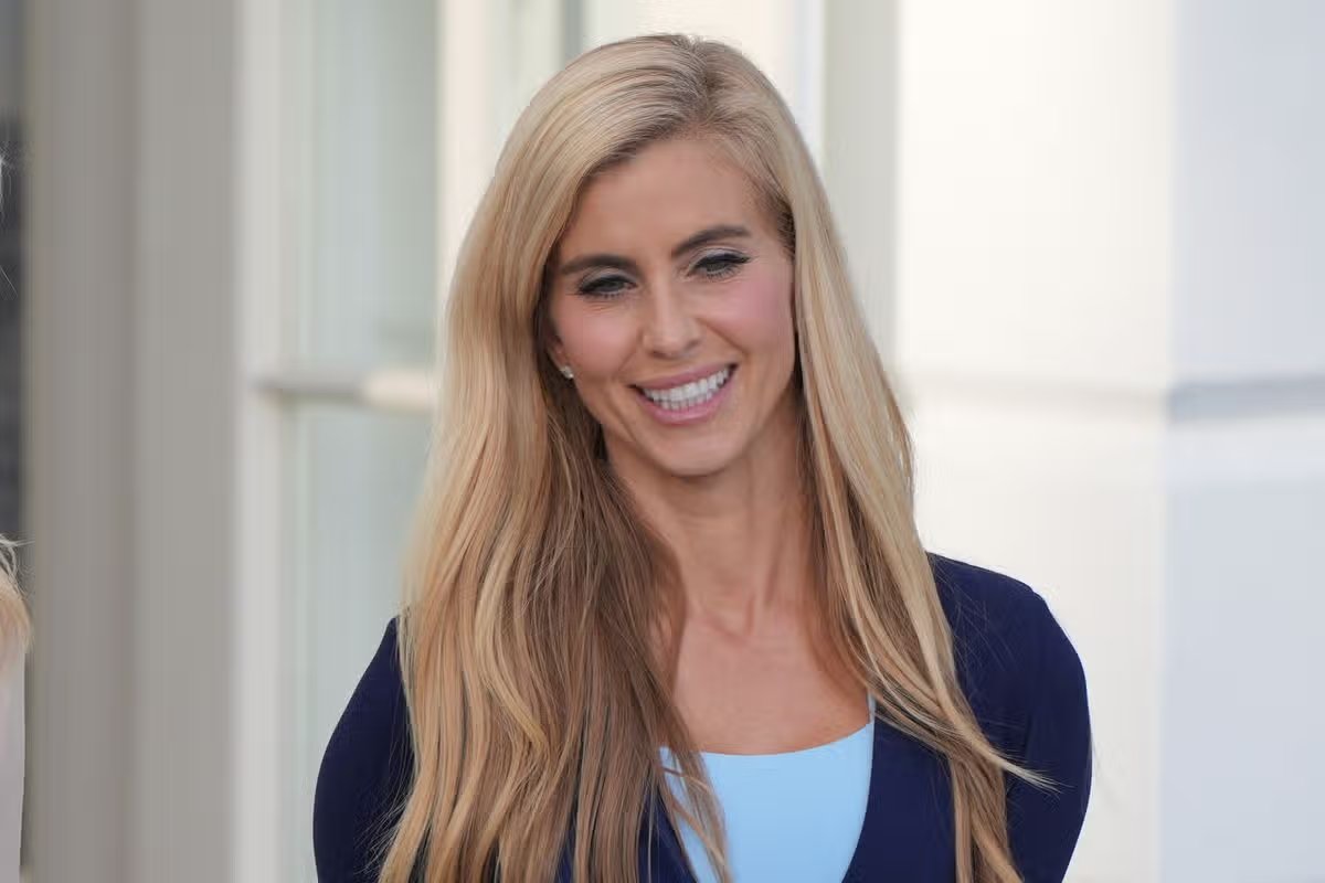 La secretaria de prensa de la Casa Blanca, Katie Zacharia, escucha al presidente Donald Trump hablar con los periodistas antes de partir a bordo del Marine One desde el jardín sur de la Casa Blanca, el lunes 12 de octubre de 2026, en Washington. (Foto AP/Alex Brandon)