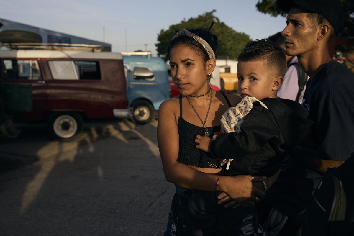 Eliante Cabrera Ramírez, de 21 años, espera un taxi grupal en Holguín, con su hijo Alan Manuel, de 2 años, y Marlon Antonio Jara, de 23.