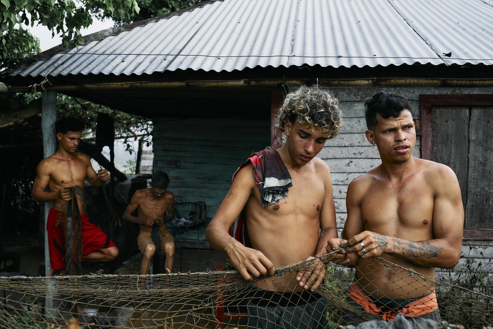 Cuatro hombres reparan una red de pesca para pescar comida para el día en Baracoa.