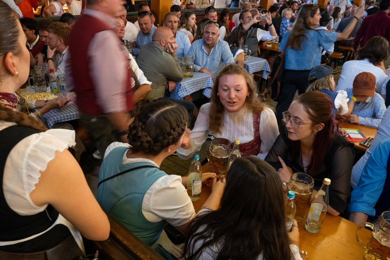 Amigos hablando en una mesa con vasos de cerveza y botellas de agua.