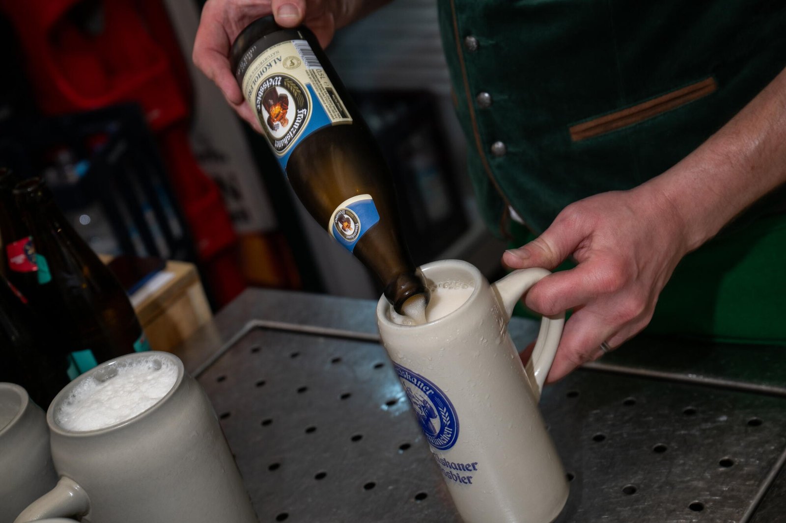 Un camarero sirve Veisper sin alcohol de una botella en una taza de gres.