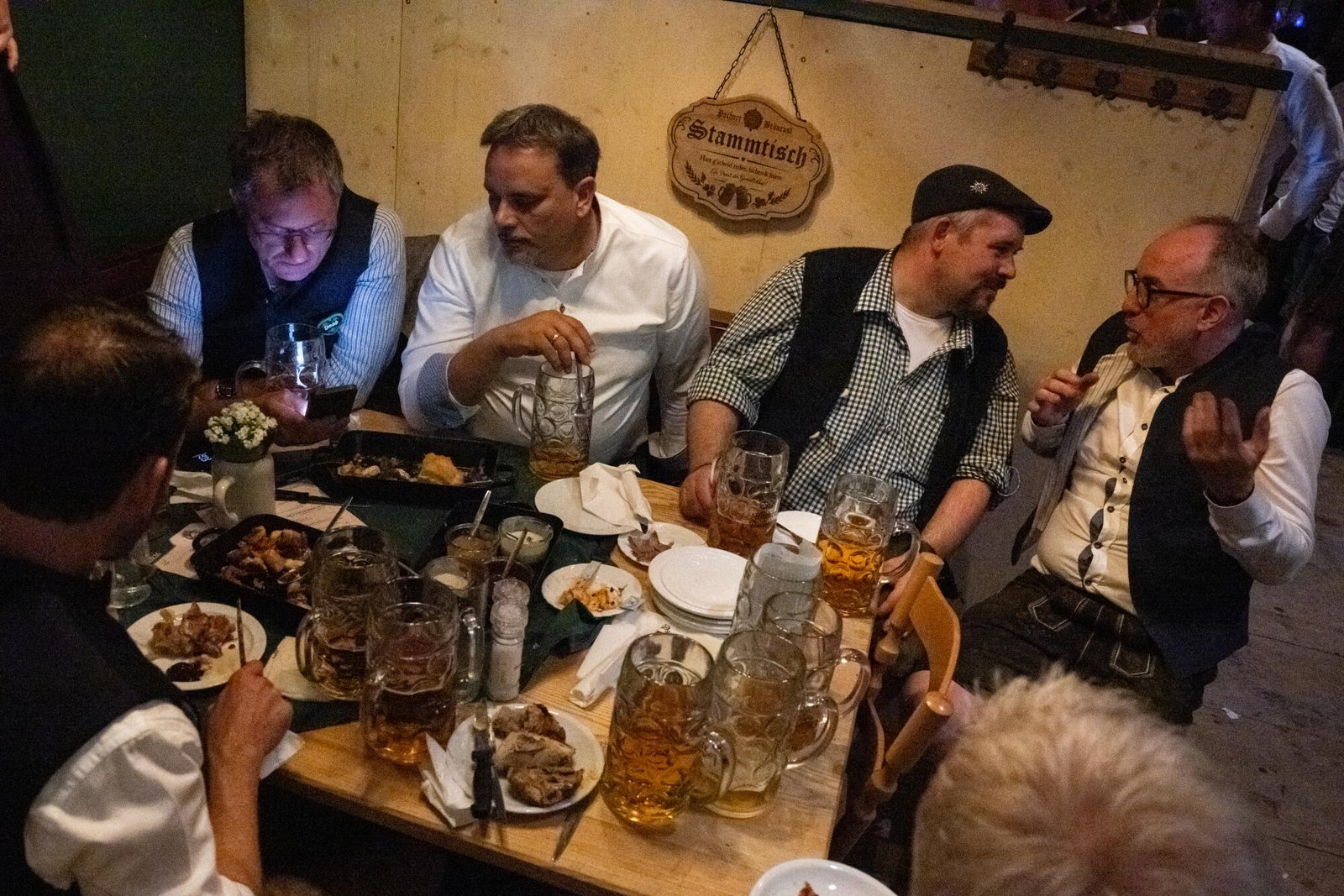 Los hombres se sientan alrededor de una mesa en una mesa informal en Pschorr Braurosl Festzelt en el Oktoberfest.