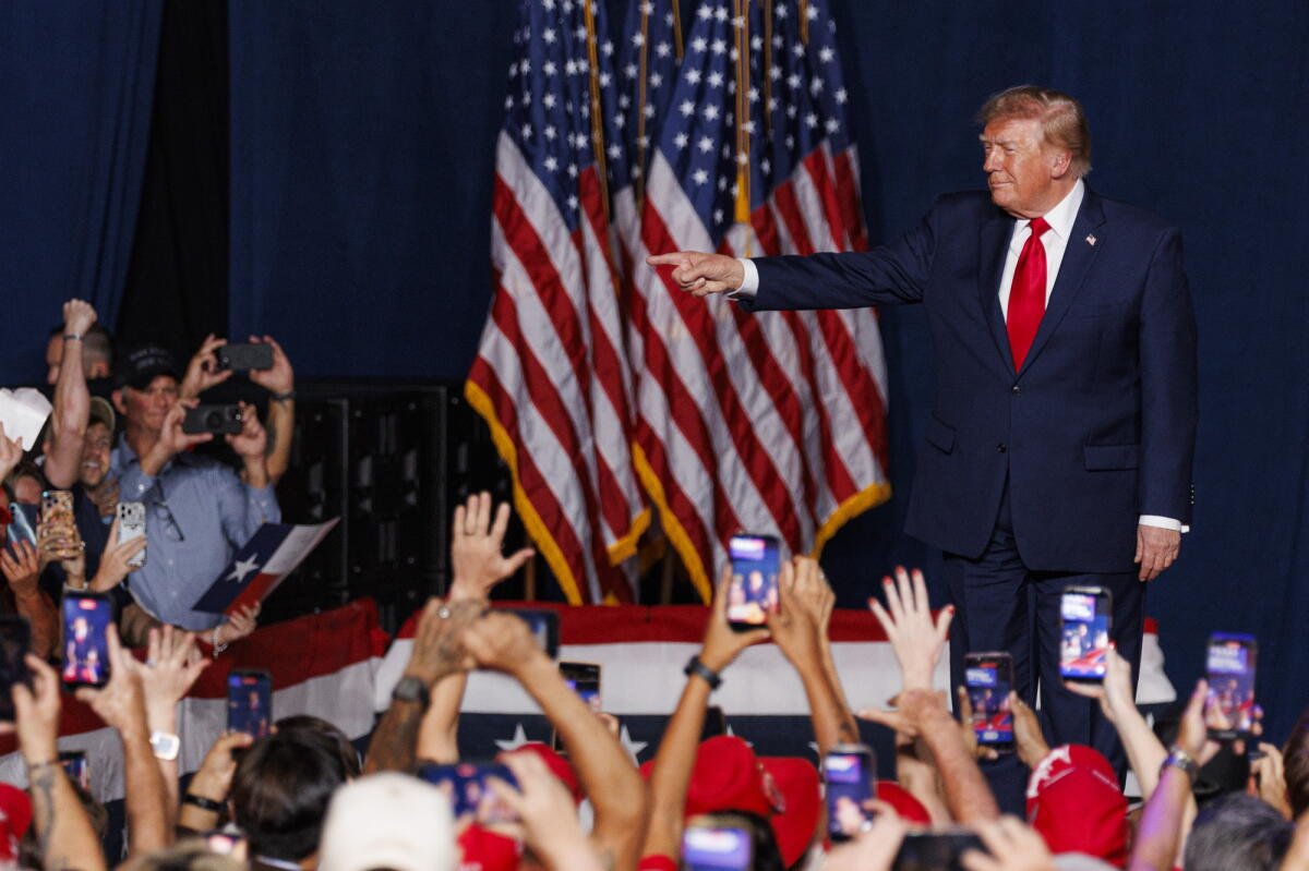 El presidente Donald J. Trump hace gestos a oleadas de fanáticos mientras camina hacia el escenario.