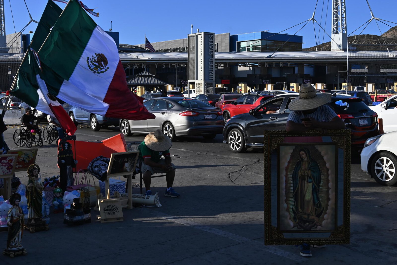 Los comerciantes venden símbolos religiosos y banderas mexicanas a los vehículos que cruzan hacia San Diego, California, desde Tijuana, México.