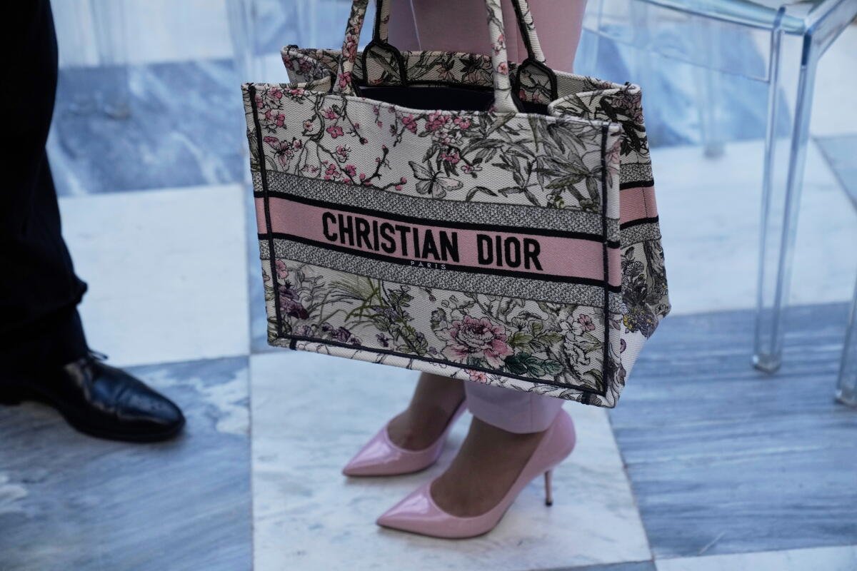 Mujer con tacones altos y pantalones rosas con un bolso de Christian Dior