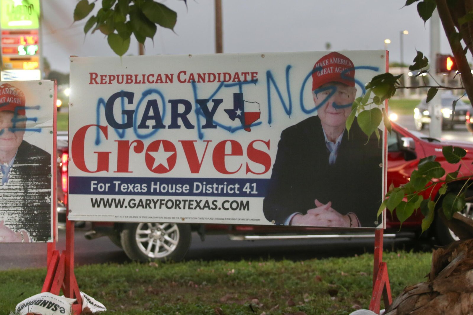 Gary Groves usa una gorra MAGA en un anuncio de campaña. lee el graffiti pintado encima del anuncio "Sin reyes."